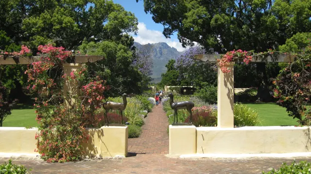 Flowering climbers frame a gateway onto a straight garden path.