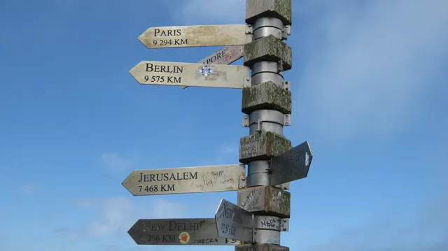 Weathered wooden boards point in different directions from a pole.