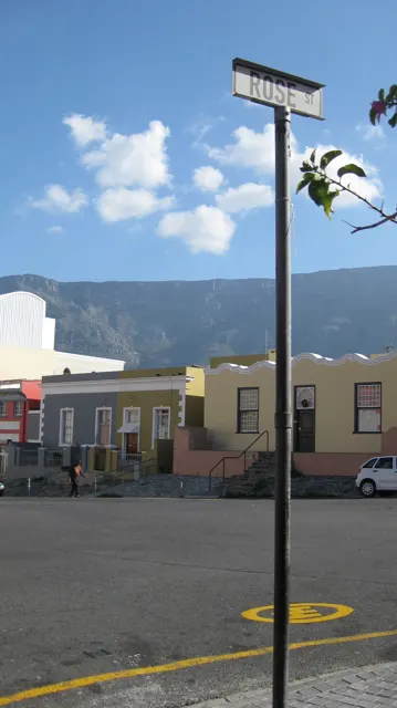A street sign rises above low colorful houses.
