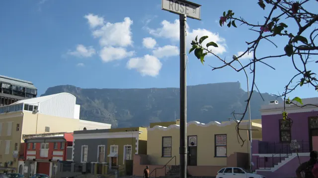 Colorful small facades stand below a broad mountain ridge.