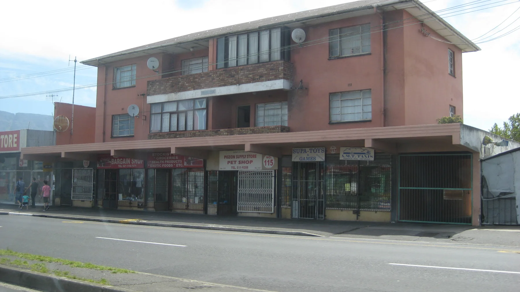 A pink multistory building rises above roadside storefronts.