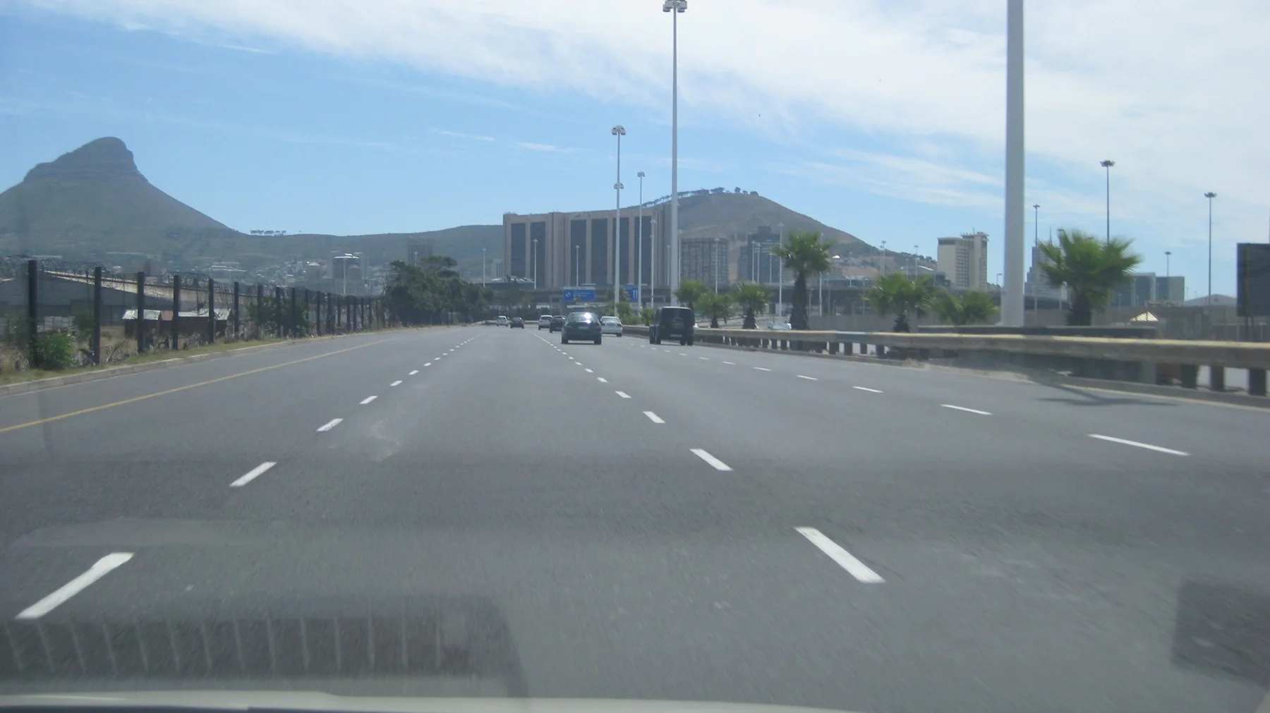A wide multilane road leads toward city buildings and hills.