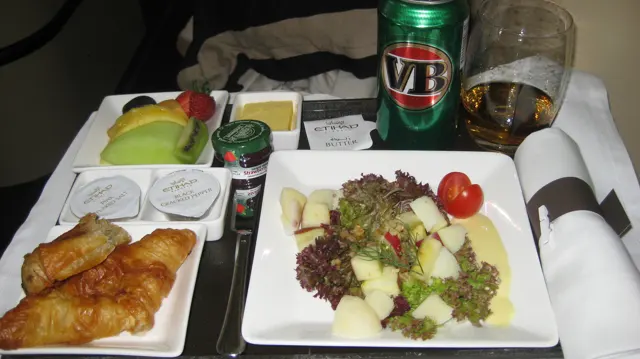 Salad, pastries, fruit and drinks fill a travel meal tray.