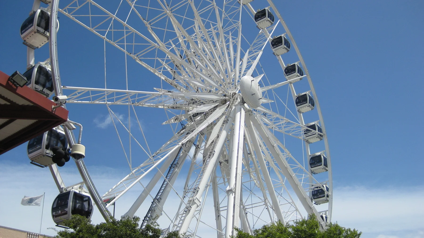 White observation-wheel spokes radiate against clear blue sky.