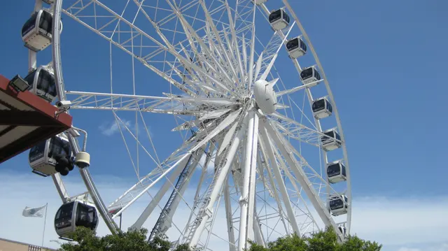 White observation-wheel spokes radiate against clear blue sky.