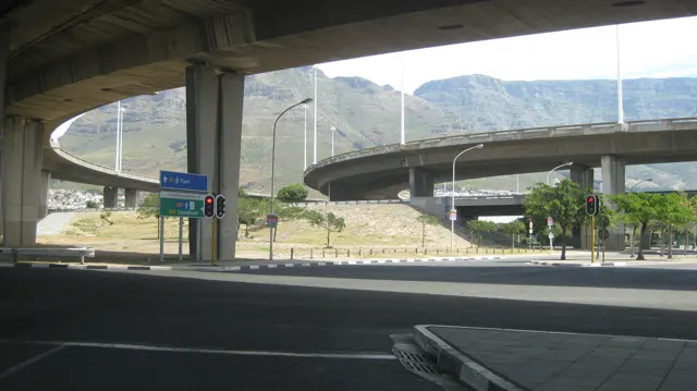 Curving elevated roads cross above a shaded city junction.