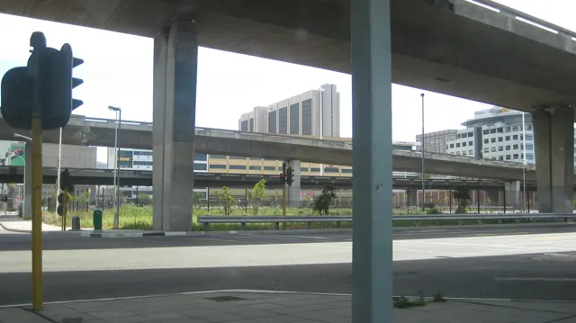 Concrete flyover pillars frame traffic lights and city buildings.