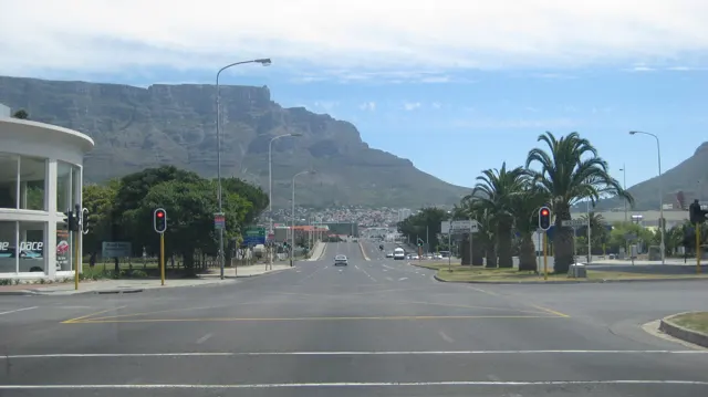 An open intersection lies beneath a flat mountain wall.