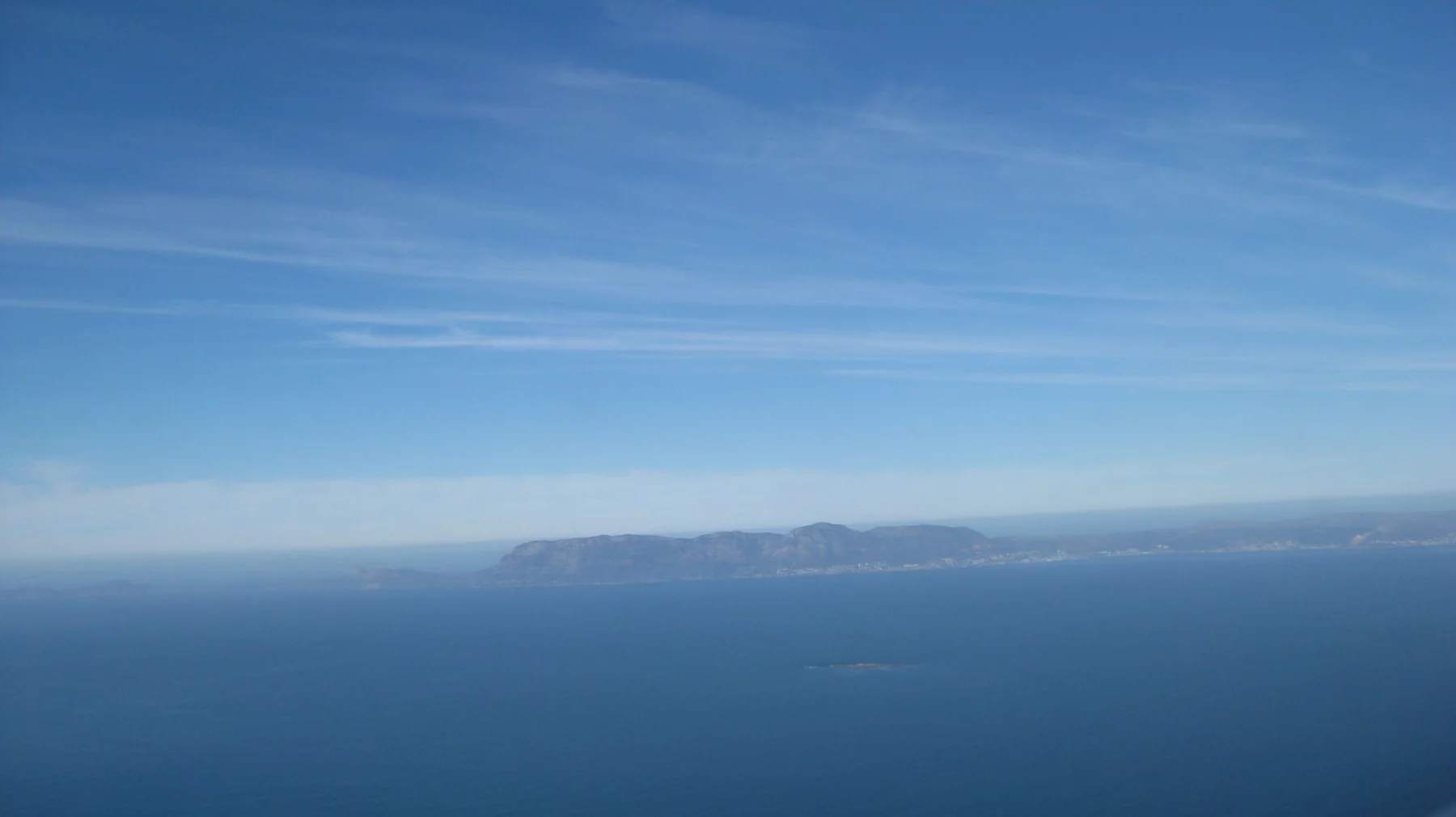 A low distant island appears across deep blue water.