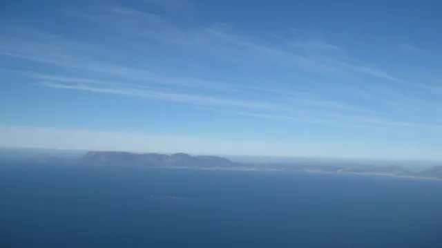 Deep blue ocean stretches toward a hazy landform on the horizon.