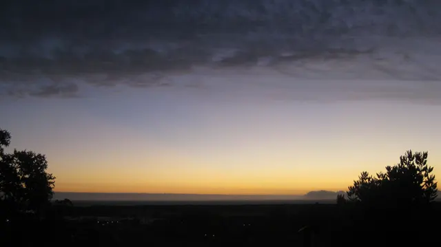 A thin golden horizon glows below dark twilight clouds.