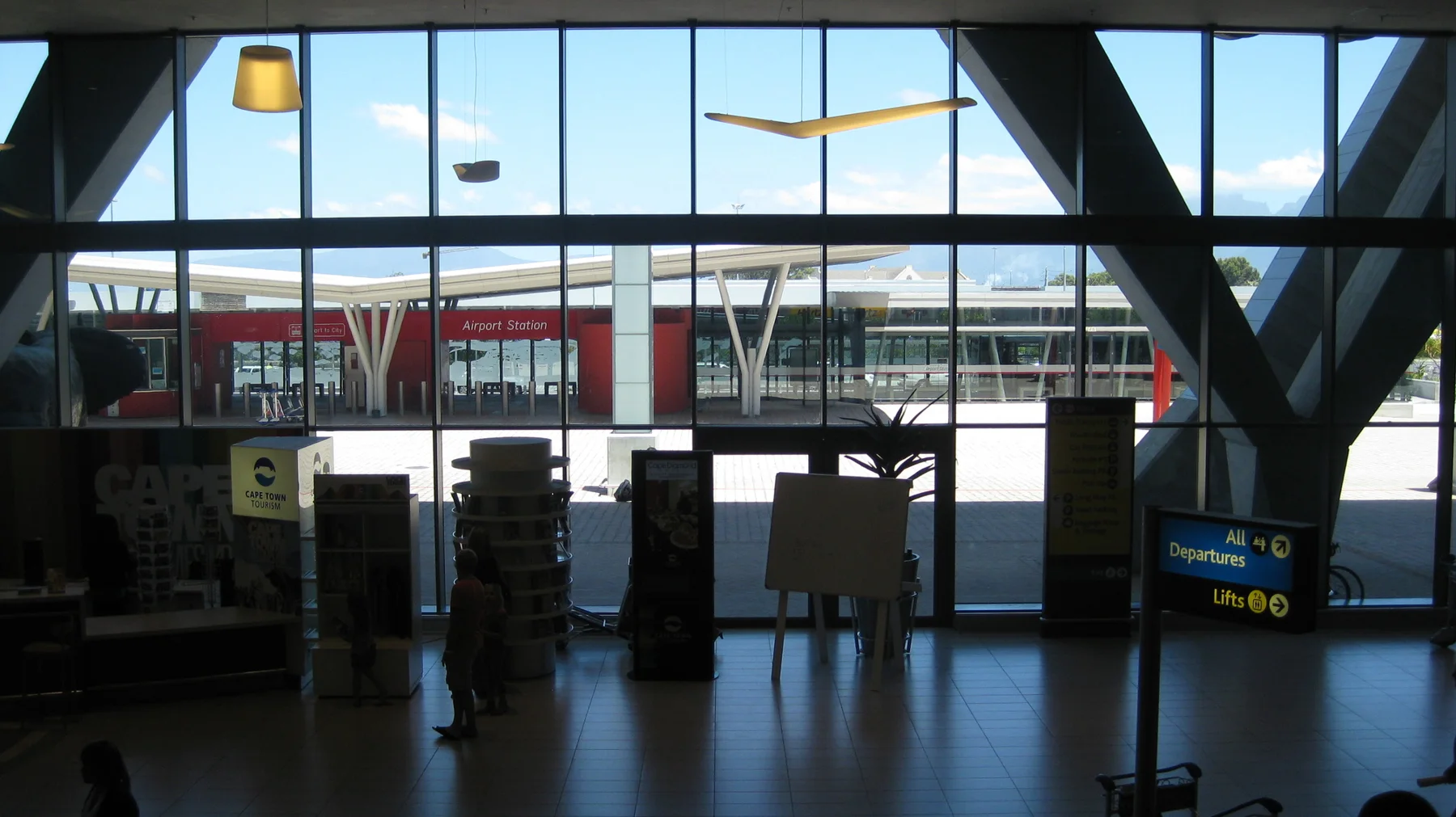 A dark interior hall opens toward large windows and visible buildings.