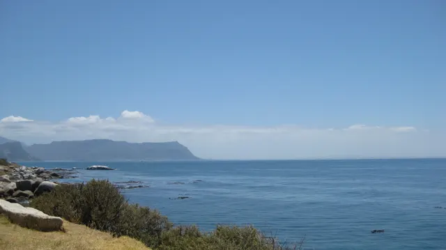 A distant flat mountain lies across calm blue water.
