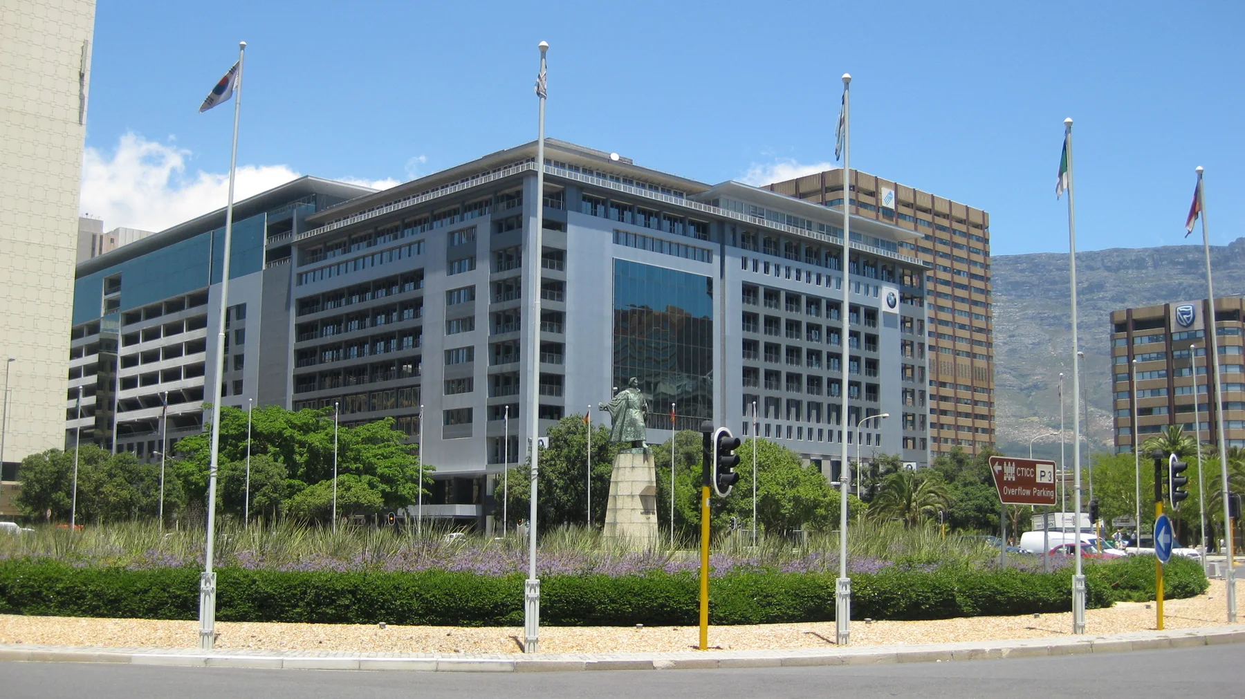 Flagpoles stand before a large windowed office building.