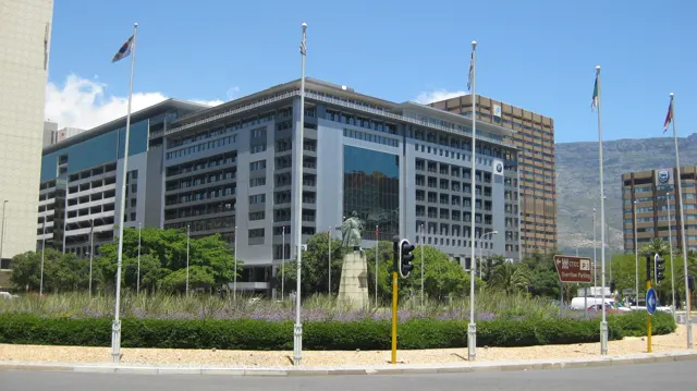Flagpoles stand before a large windowed office building.