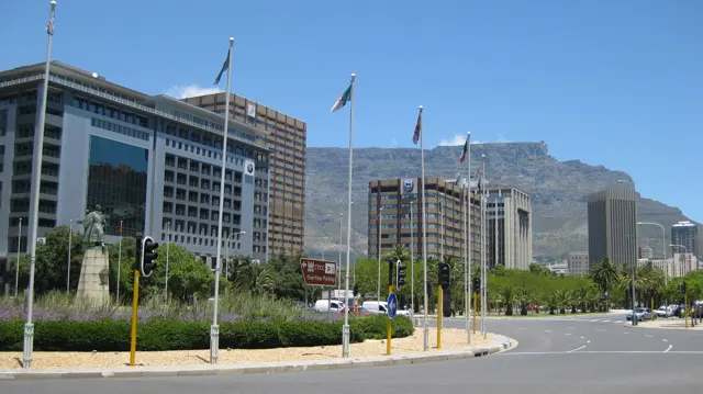 A street curves around landscaped grounds below office towers.