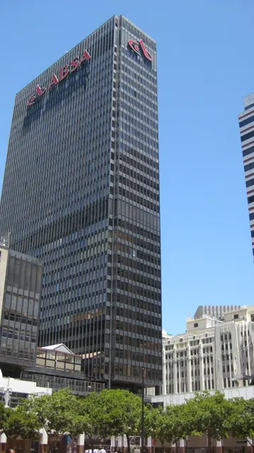 A tall glass office tower rises above lower city buildings.