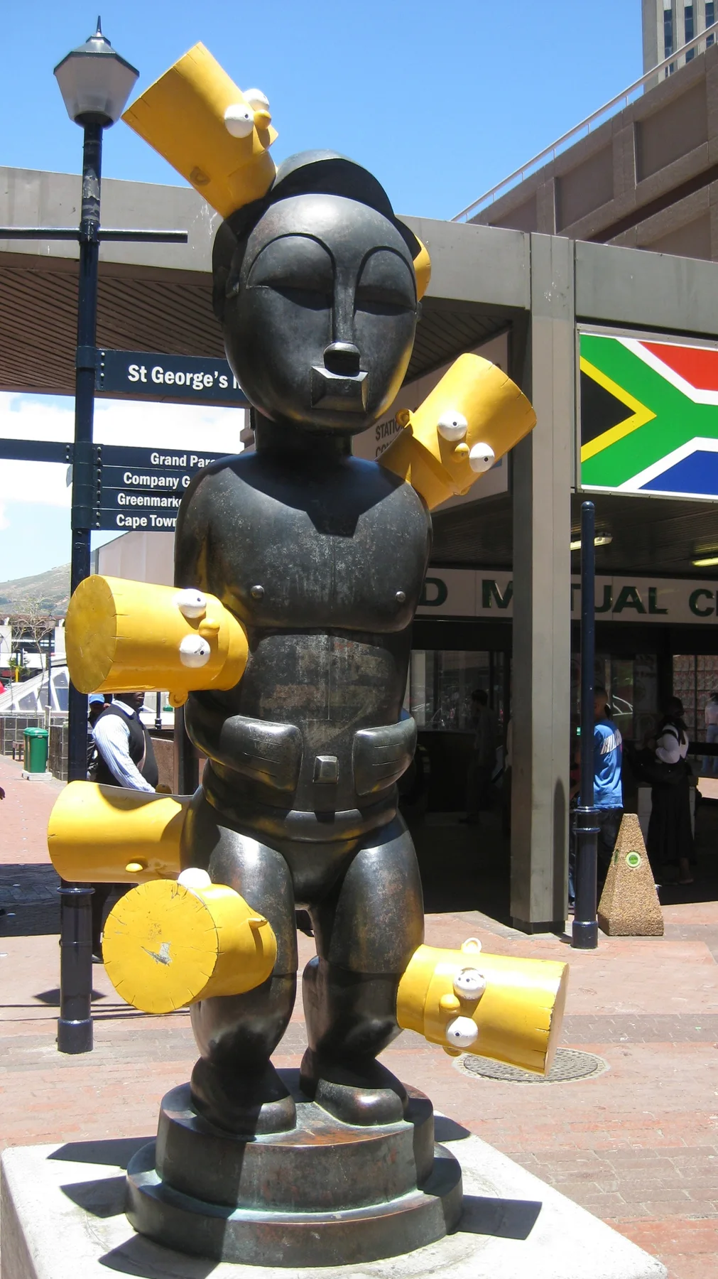 A dark stylized boxer sculpture wears bright yellow gloves.