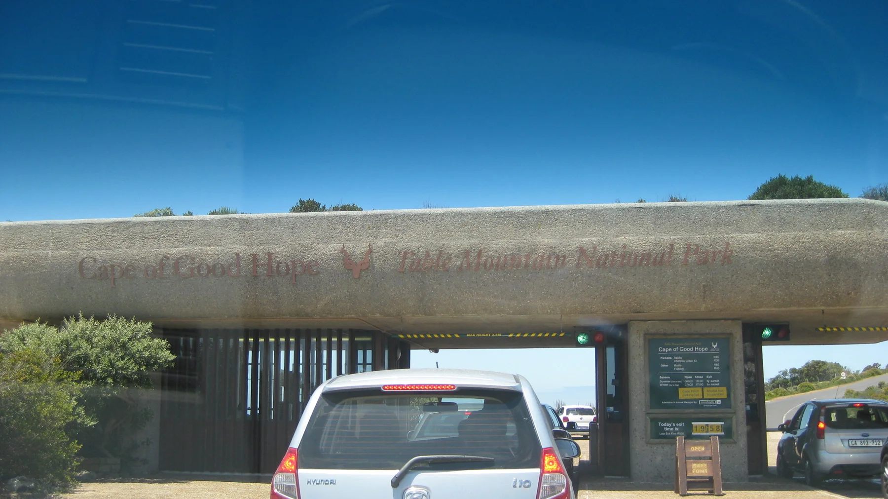 A car waits at an entry booth beneath a low broad roof.