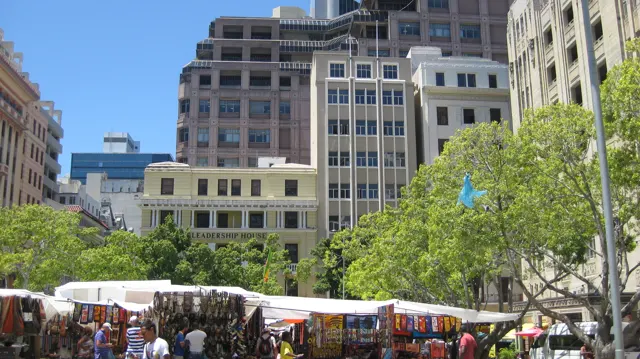 Market stalls fill a square beneath tall pale buildings.