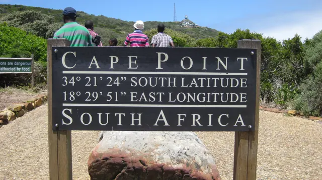 A dark Cape Point sign displays geographic coordinates beside a path.