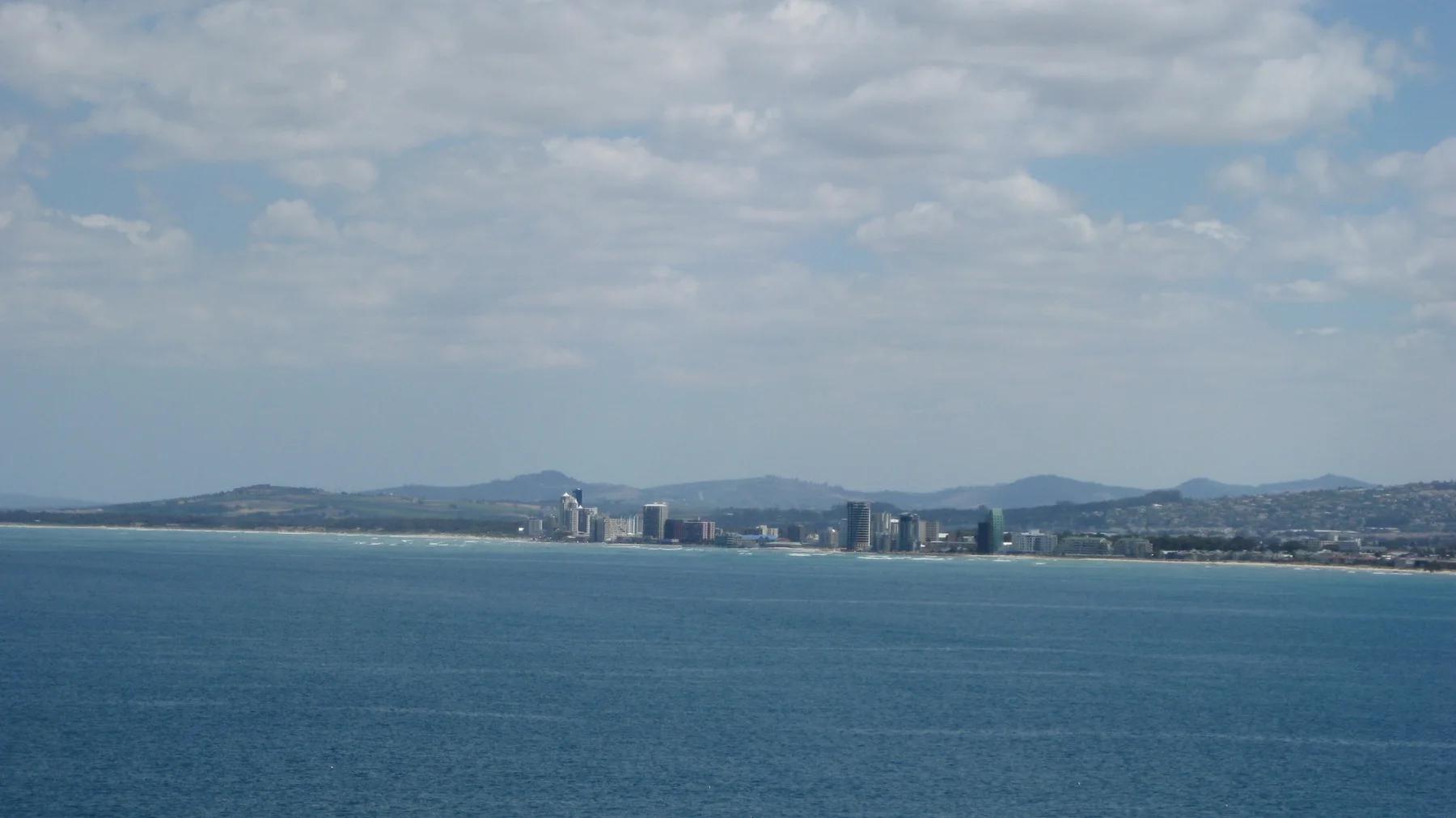 Distant waterfront towers line a broad blue bay.