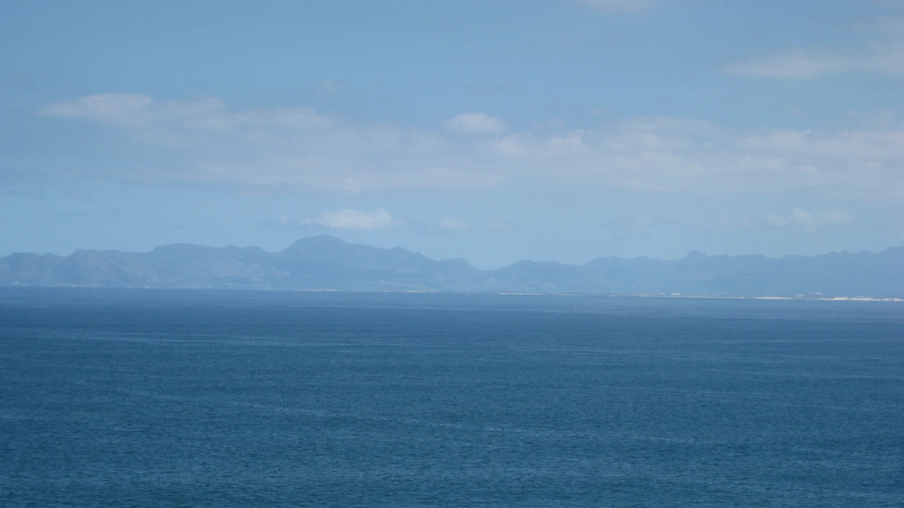 A hazy mountain line stretches across deep blue water.