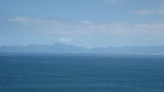 A hazy mountain line stretches across deep blue water.