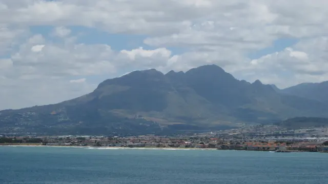 A rugged mountain range rises above shoreline development.