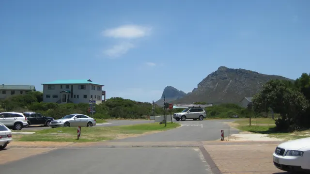 An open road junction passes low buildings between rocky hills.