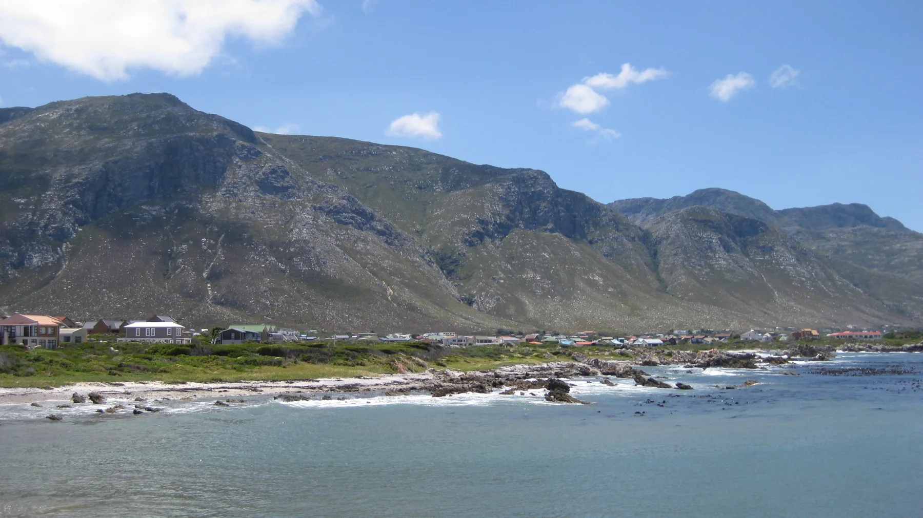 A long mountain ridge rises behind a narrow coastal strip.