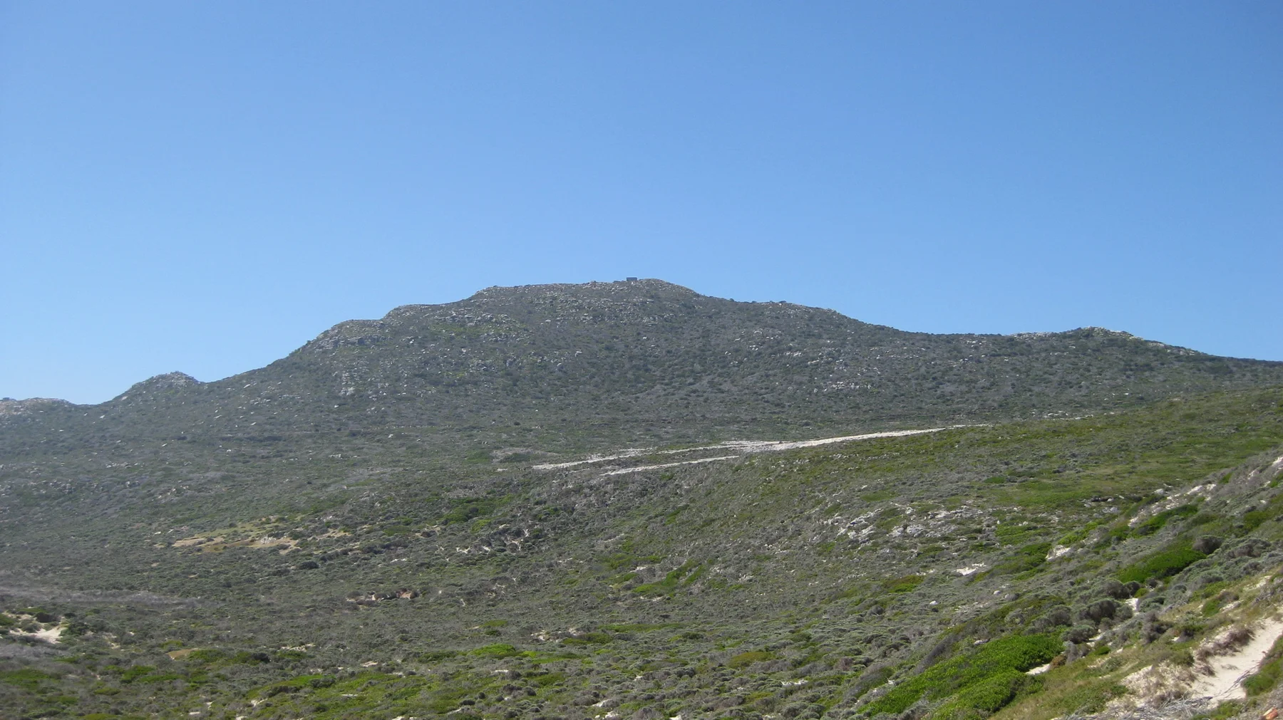 A long stony ridge rises above low coastal vegetation.