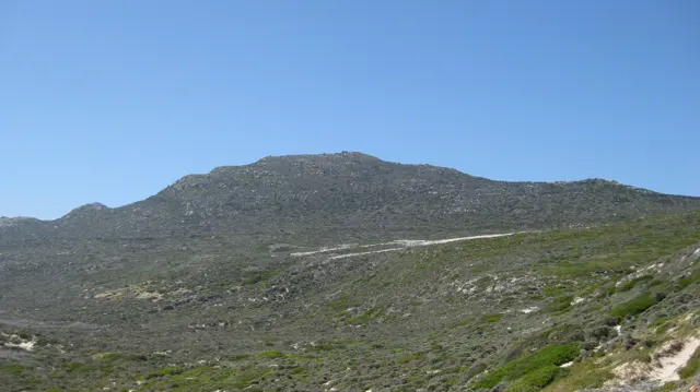 A long stony ridge rises above low coastal vegetation.