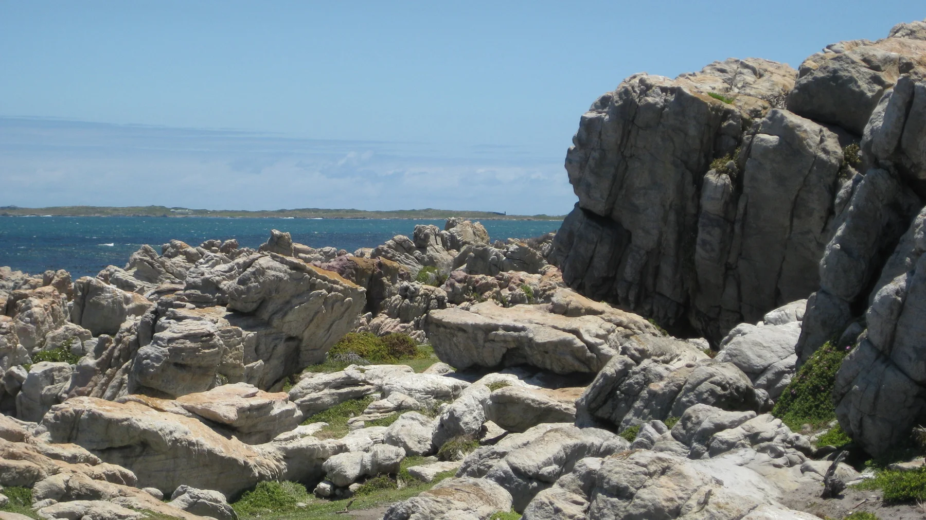 A sandy passage winds among large coastal boulders.