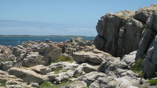 A sandy passage winds among large coastal boulders.