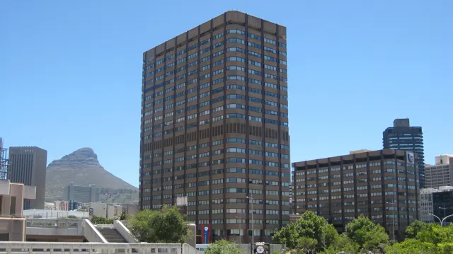 A dark rectangular office tower stands against clear blue sky.