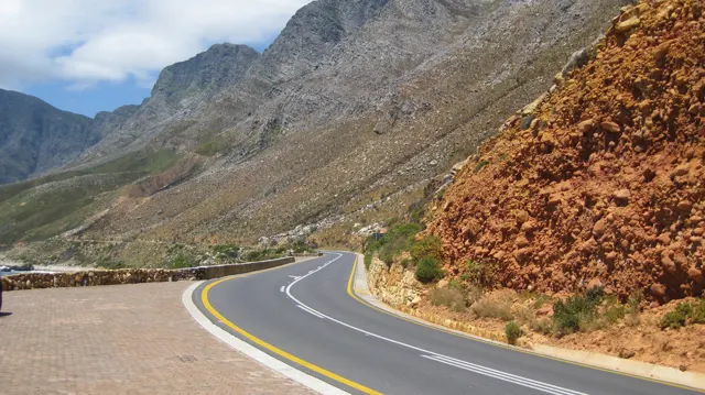 A curving road runs between orange exposed rock and mountain slopes.