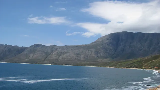 A steep mountain wall encloses a calm blue bay.
