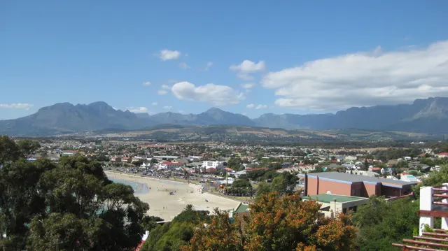 Town buildings spread below distant mountains and white clouds.