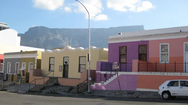 Pink and cream houses stand beside a street below the mountain.
