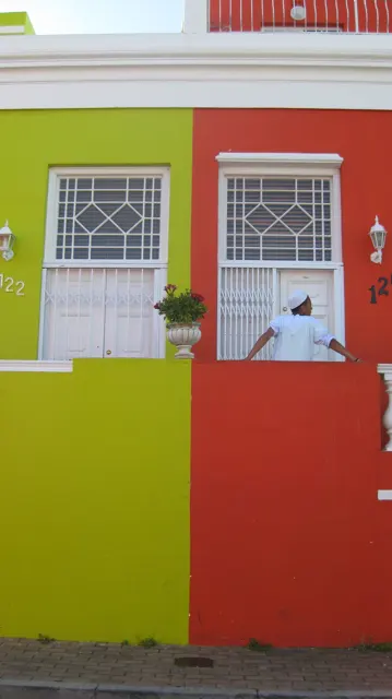 Adjacent yellow and red facades frame barred windows and doors.