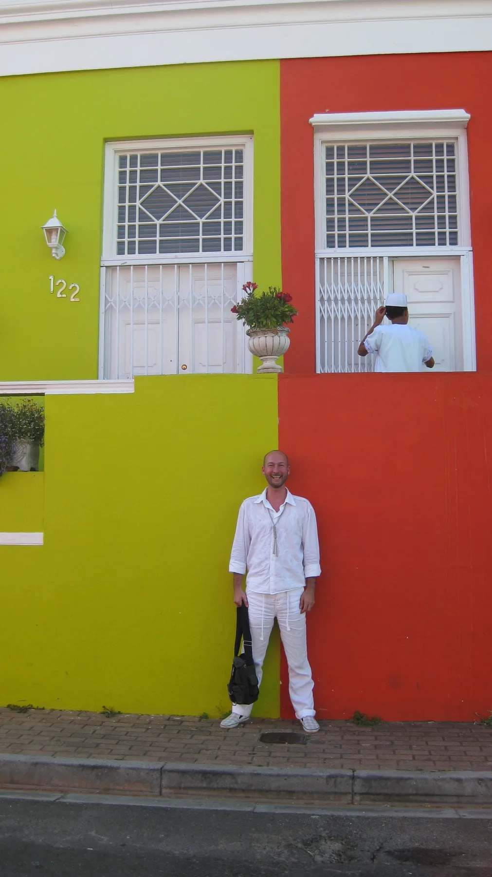 A person dressed in white stands before yellow and red walls.