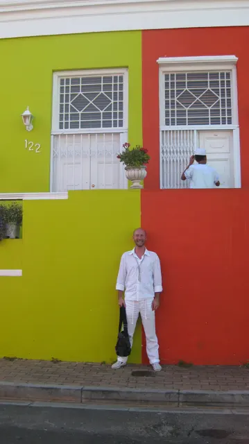 A person dressed in white stands before yellow and red walls.