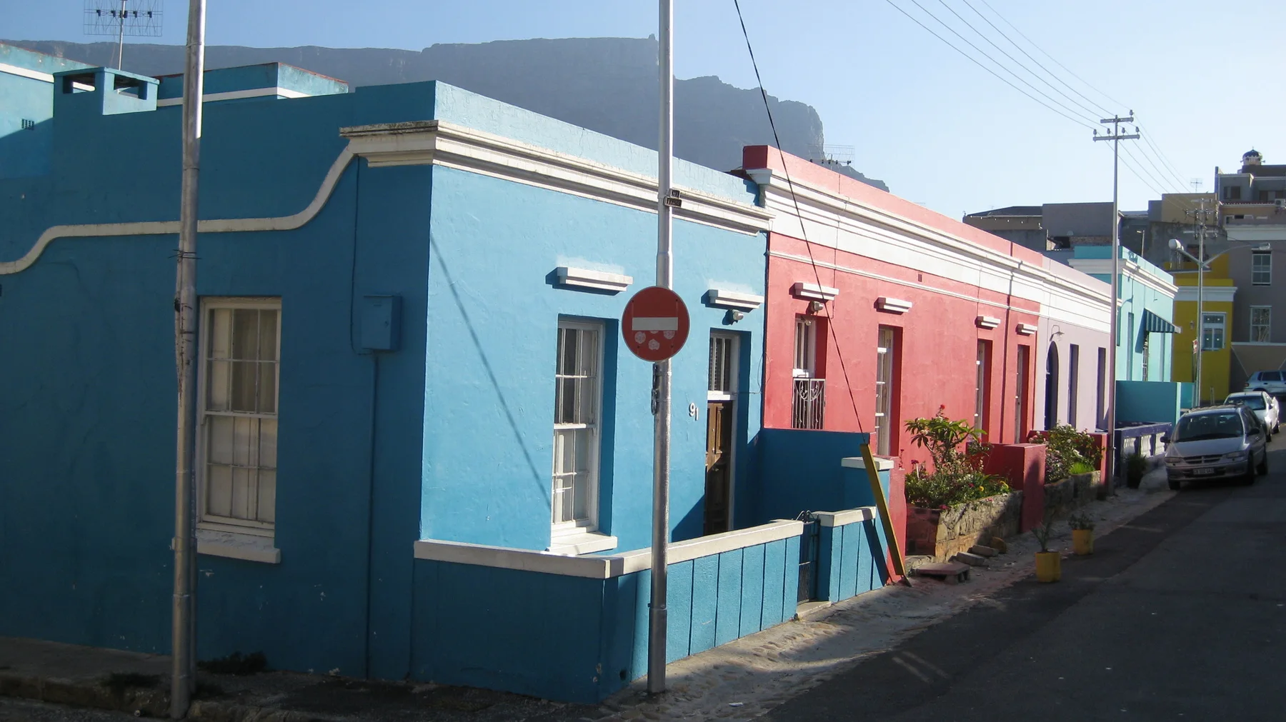 Blue and pink houses meet at a street corner.