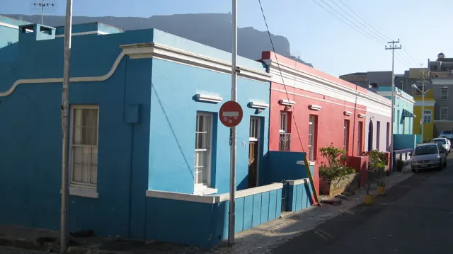 Blue and pink houses meet at a street corner.