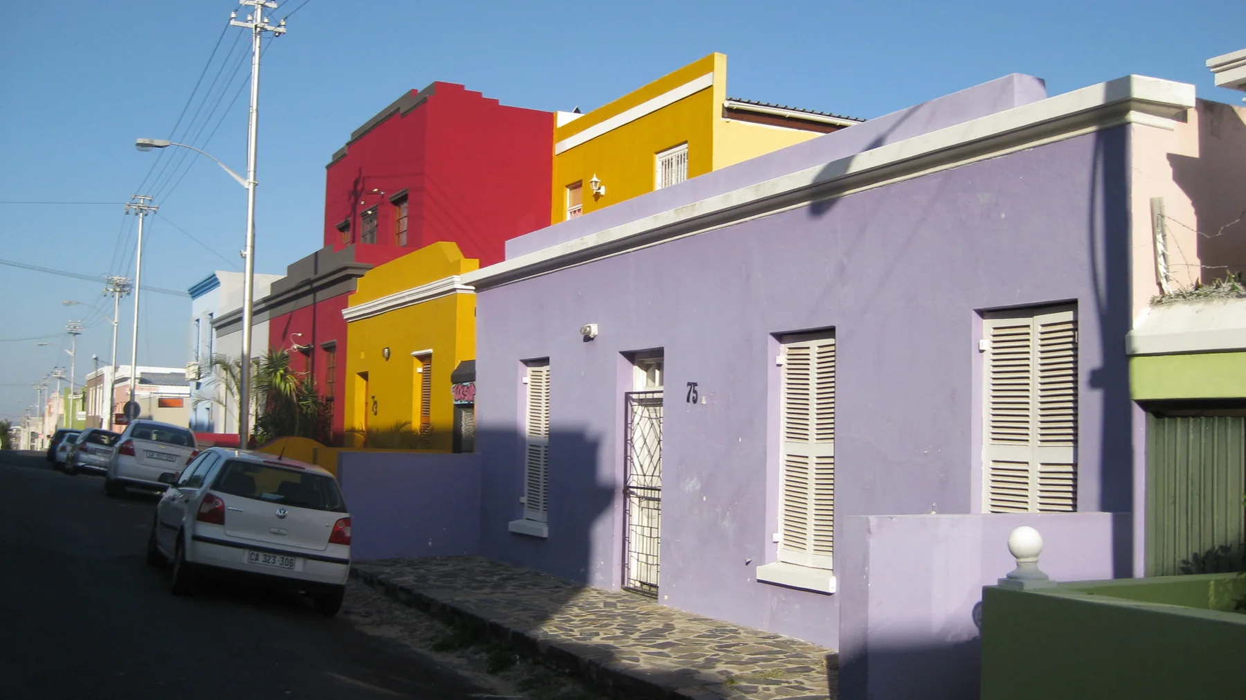 Lavender, yellow and red facades line a sloping street.