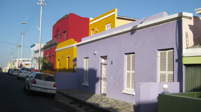 Lavender, yellow and red facades line a sloping street.