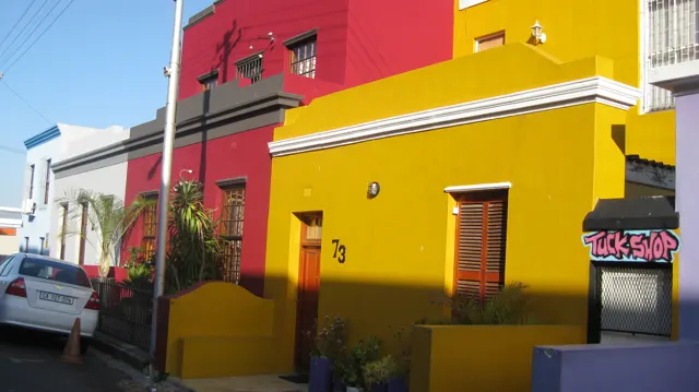 A vivid yellow house numbered seventy-three stands beside a red facade.