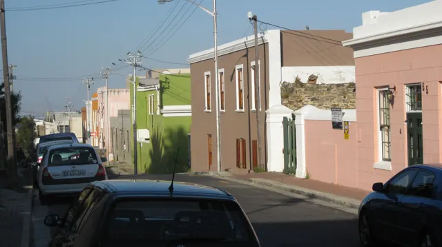 Pastel houses and parked cars line a downhill street.