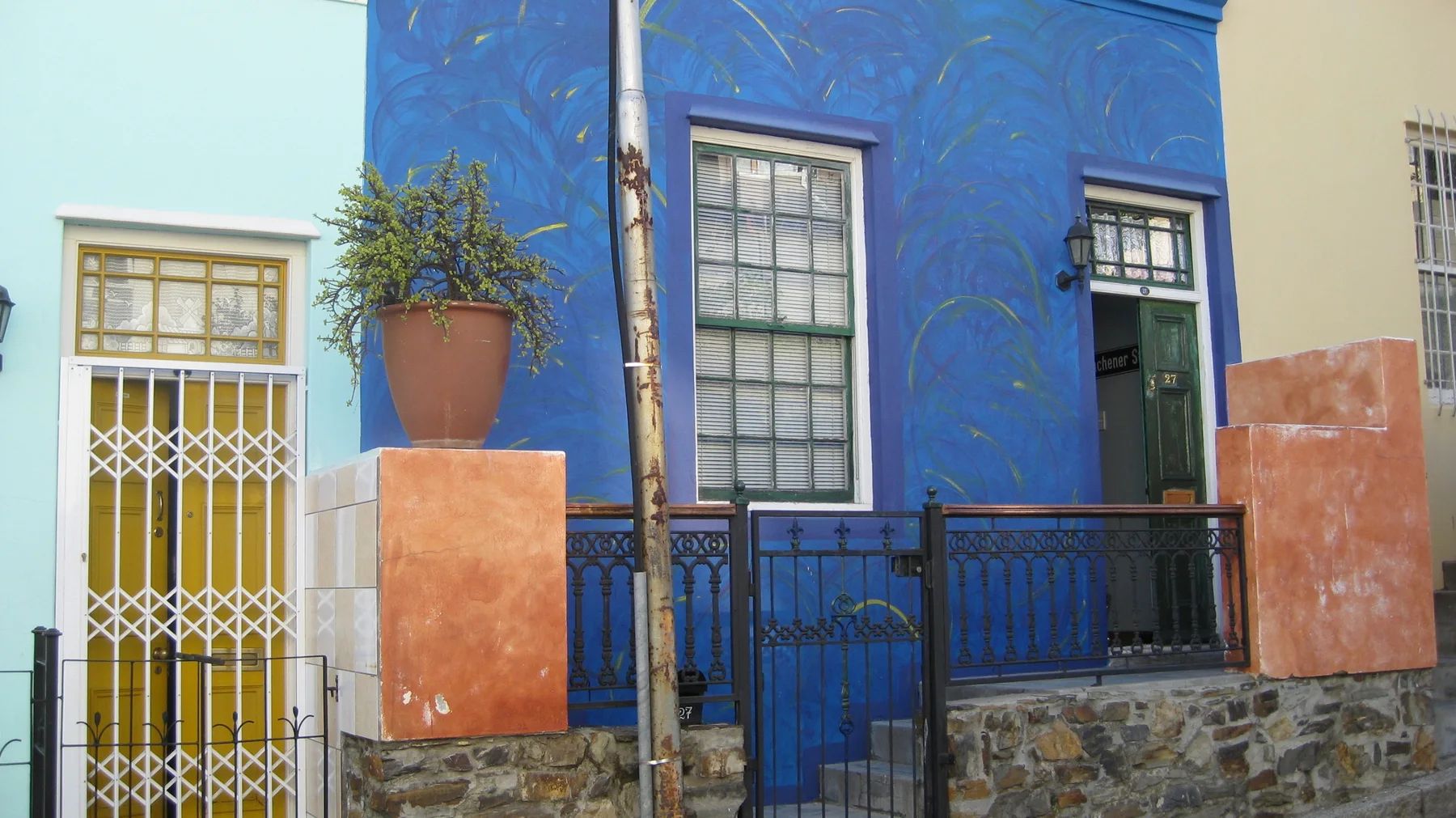 A blue facade stands behind orange posts and dark railings.